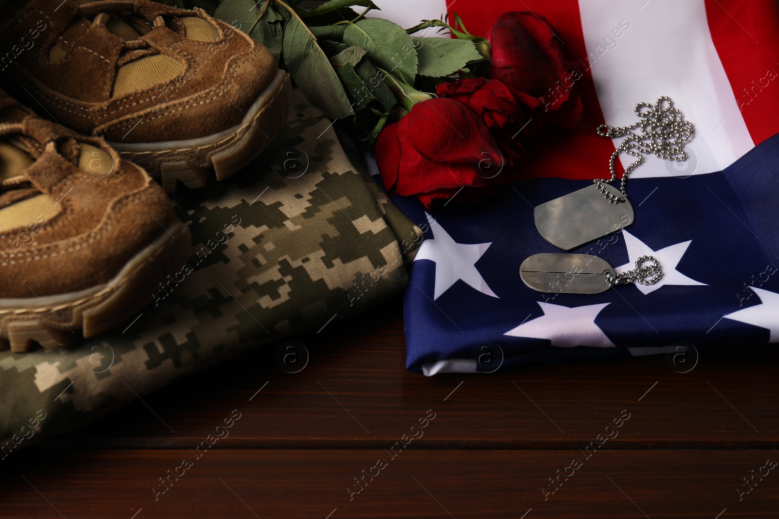 Photo of Veterans day. Army tokens, American flag, roses and military uniform on wooden table, closeup