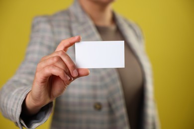 Photo of Woman holding blank business card on yellow background, closeup. Mockup for design