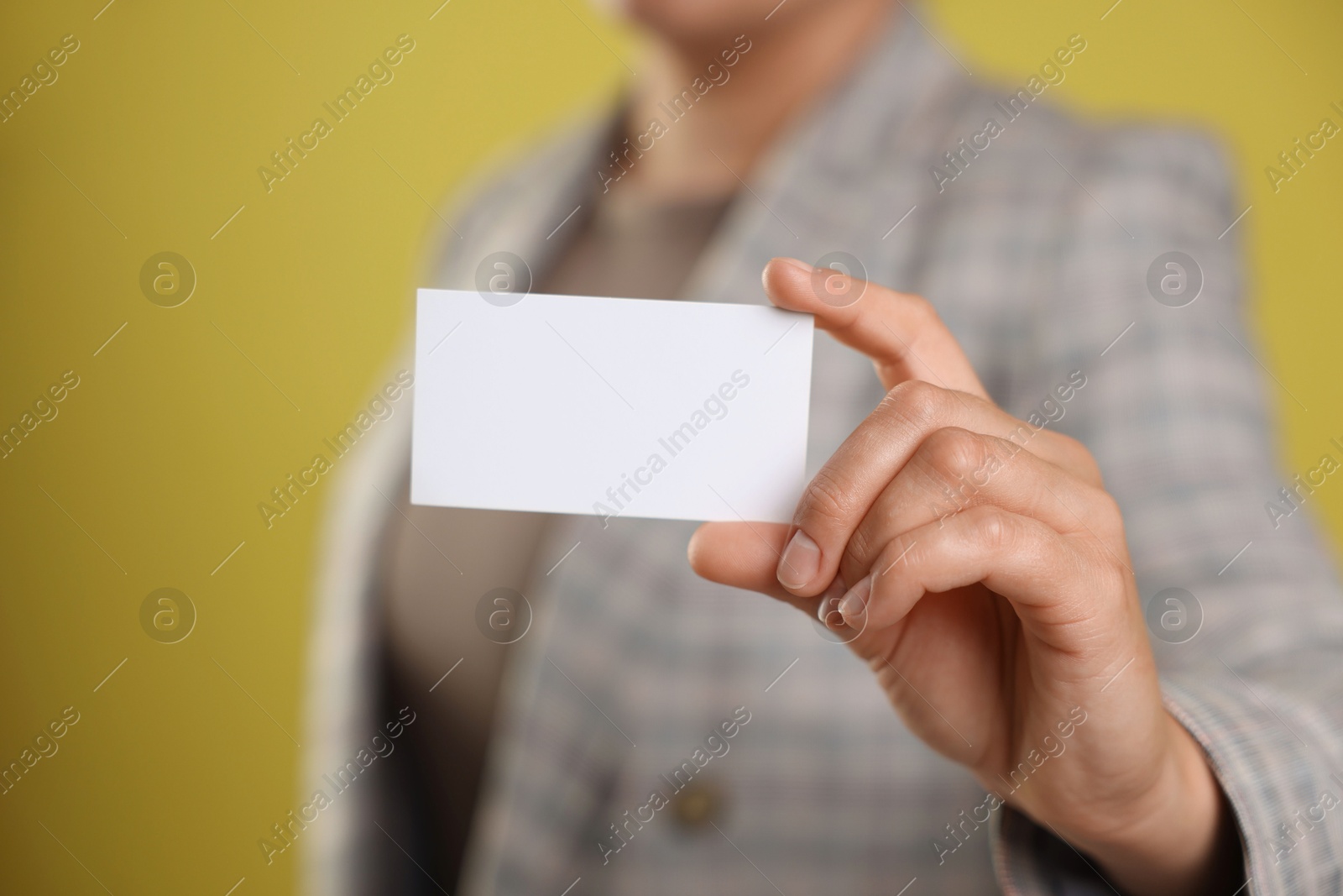 Photo of Woman holding blank business card on yellow background, closeup. Mockup for design