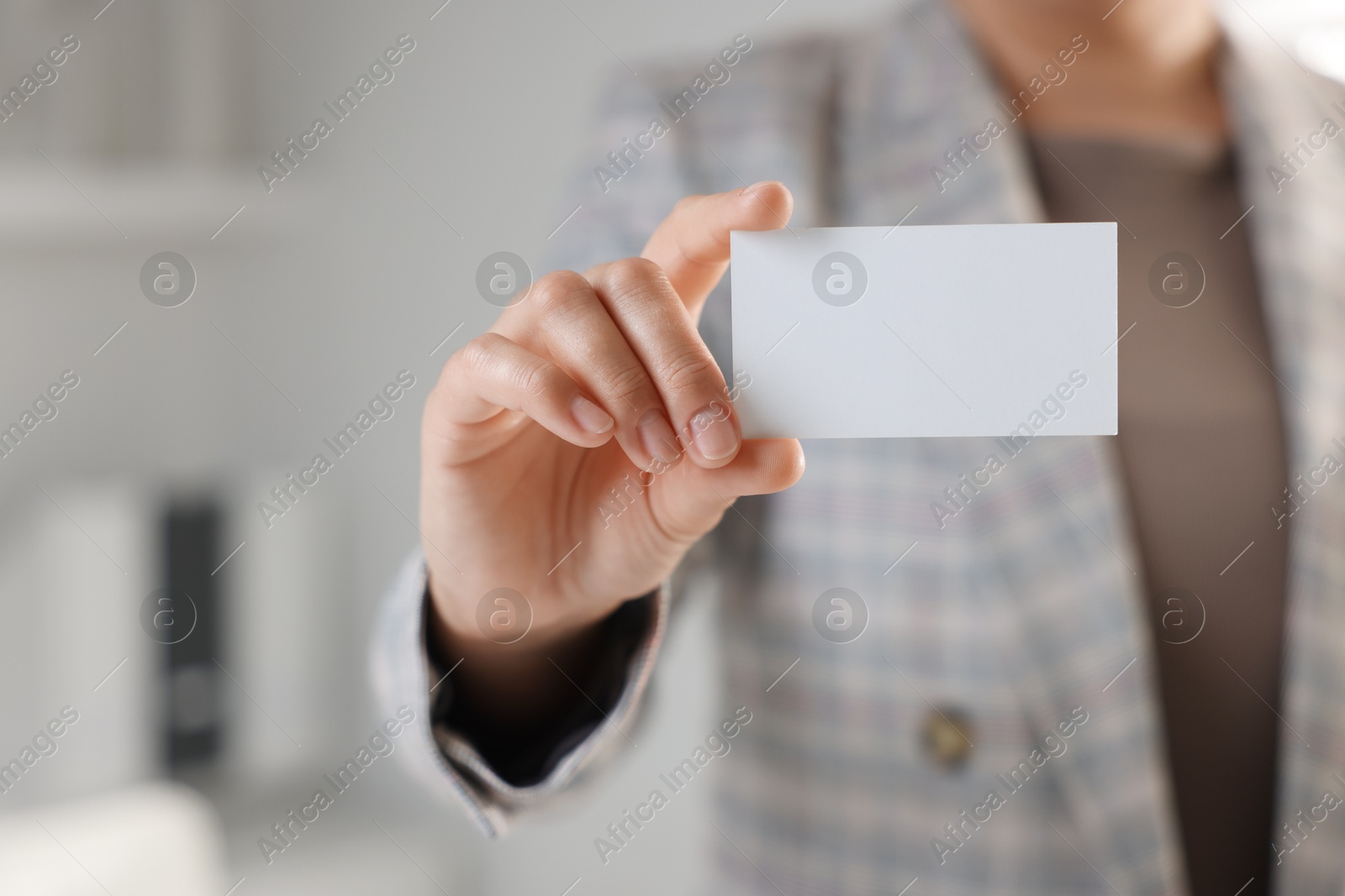 Photo of Woman holding blank business card in office, closeup. Mockup for design