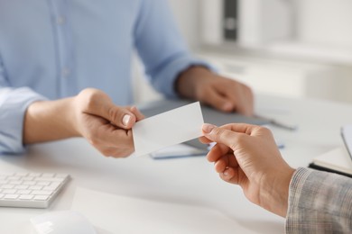 Photo of Man giving business card to woman at table in office, closeup. Mockup for design