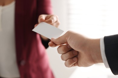 Photo of Woman giving business card to man in office, closeup. Mockup for design