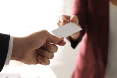 Woman giving business card to man in office, closeup. Mockup for design