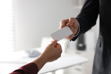 Photo of Man giving business card to woman in office, closeup. Mockup for design