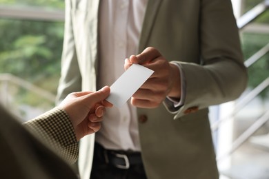 Photo of Man giving business card to woman in office, closeup. Mockup for design