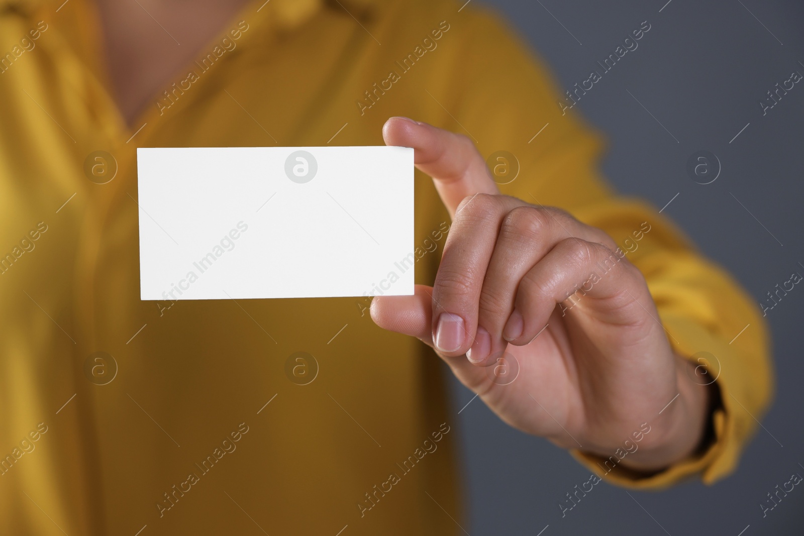 Photo of Woman holding blank business card on grey background, closeup. Mockup for design