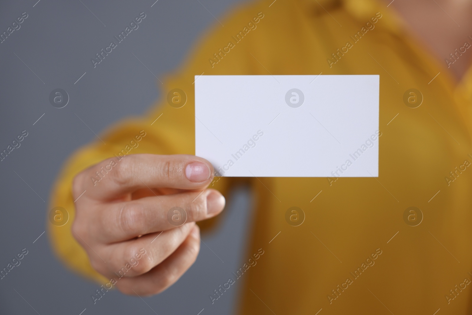 Photo of Woman holding blank business card on grey background, closeup. Mockup for design