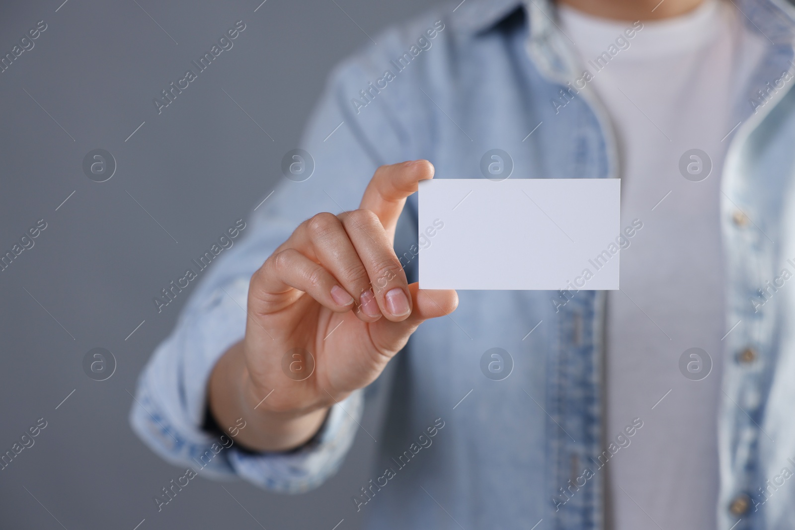 Photo of Woman holding blank business card on grey background, closeup. Mockup for design