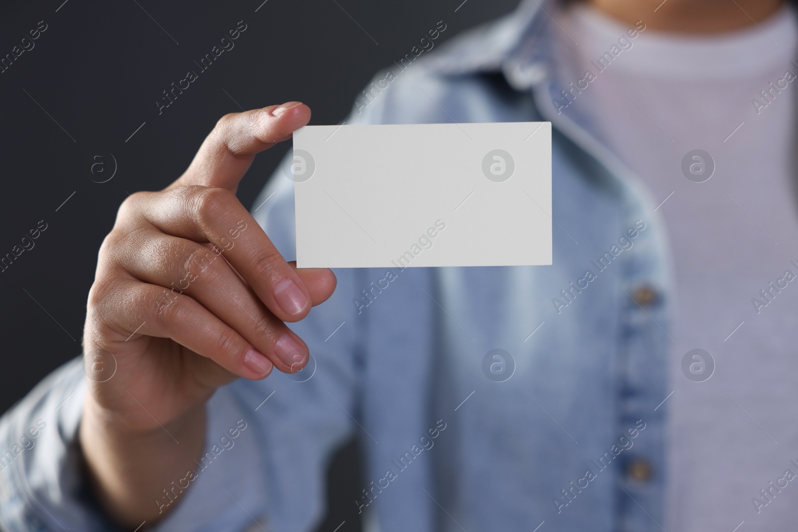 Photo of Woman holding blank business card on grey background, closeup. Mockup for design