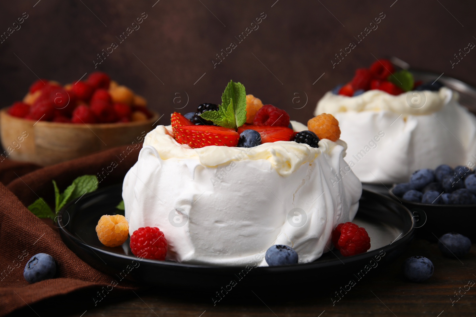 Photo of Pavlova cake (meringue dessert) with whipped cream, fresh berries and mint on wooden table, closeup