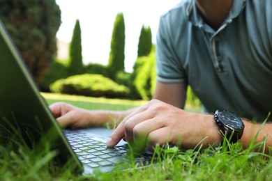 Photo of Man using laptop on green lawn outdoors, closeup