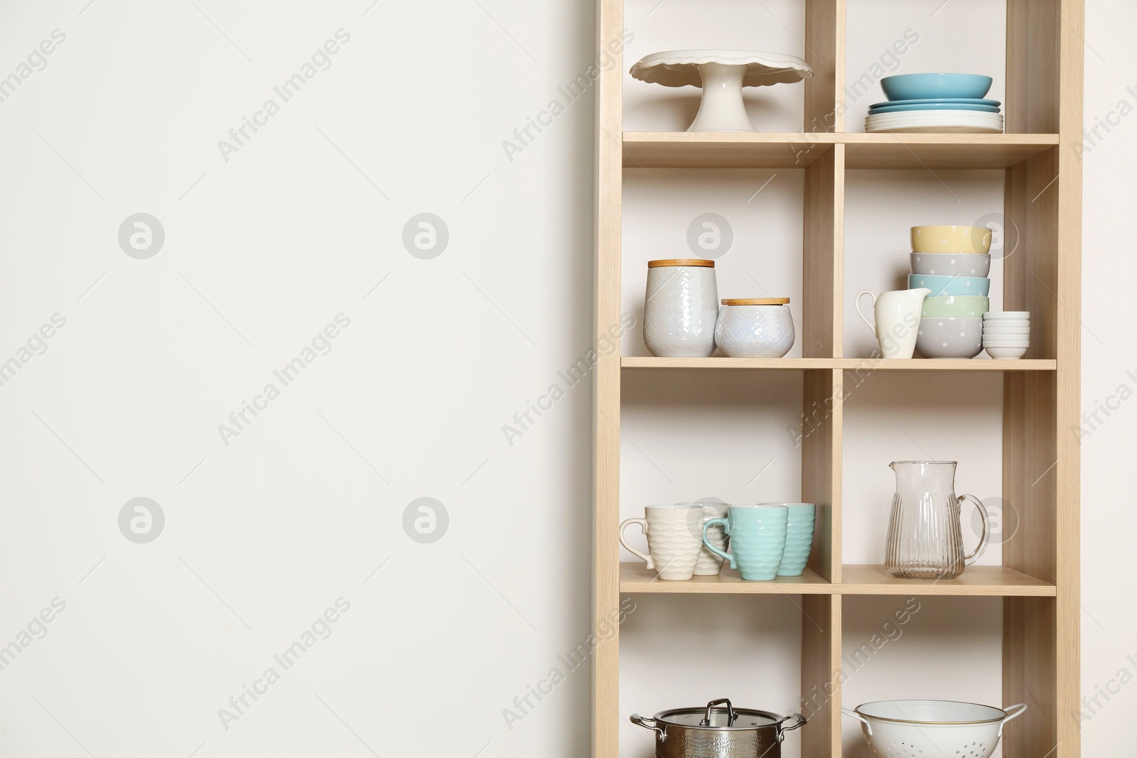 Photo of Wooden shelving unit with kitchenware on white background, space for text