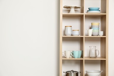 Photo of Wooden shelving unit with kitchenware on white background, space for text