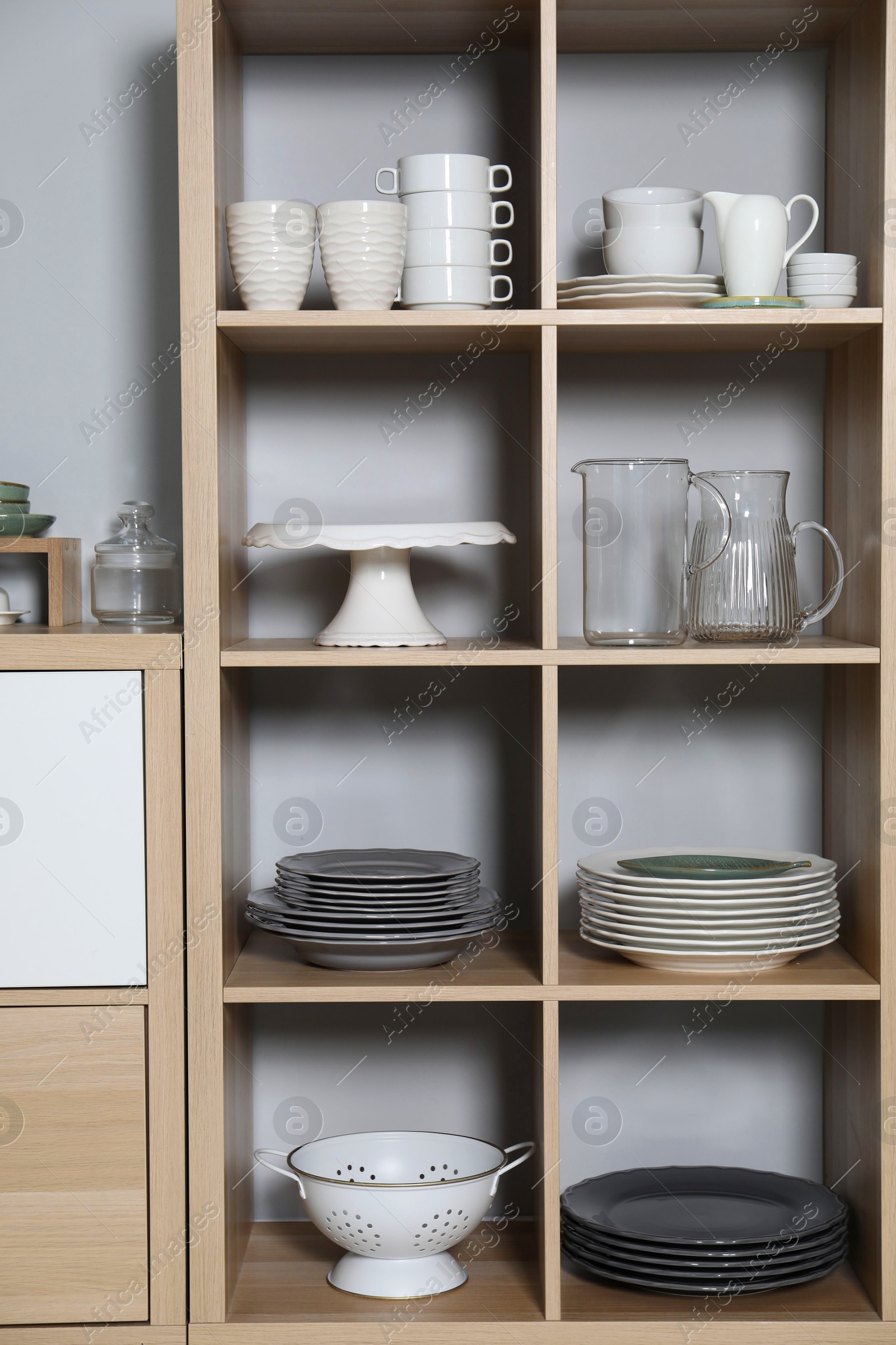 Photo of Wooden shelving unit with kitchenware near grey wall indoors