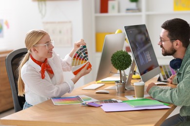 Designers with color samples working together at table in office