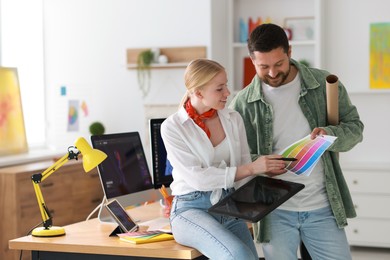 Photo of Designers with tablet and color palette working together in office