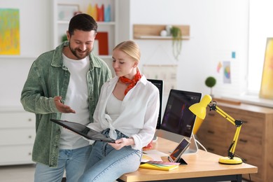 Professional designers working with tablet together in office