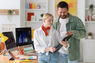 Professional designers working with tablet together in office