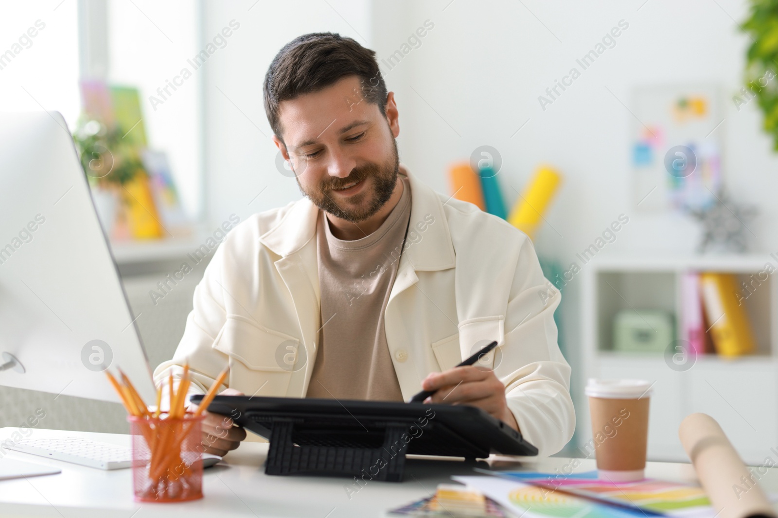 Photo of Designer working with tablet at table in office