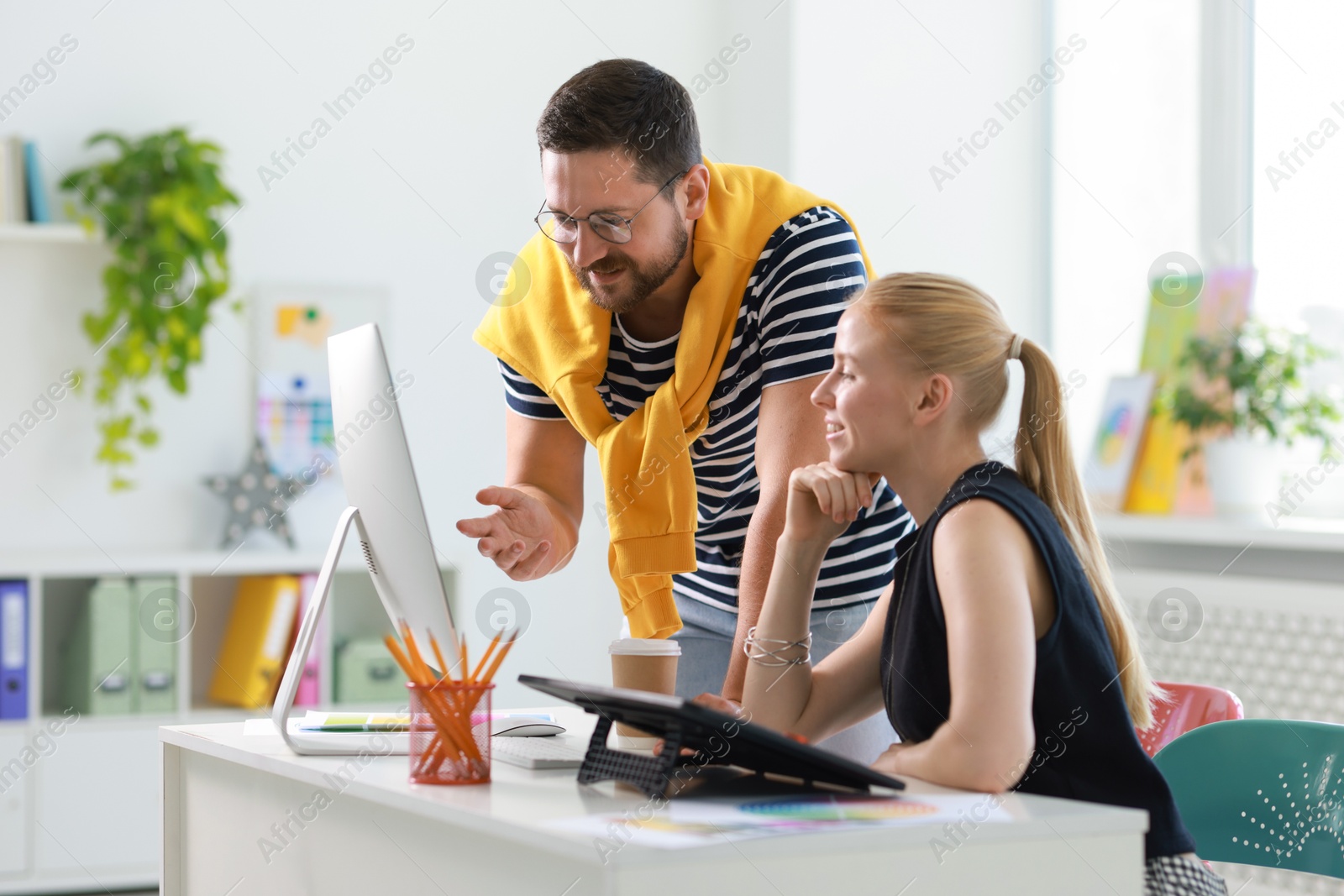 Photo of Smiling designers discussing project together in office