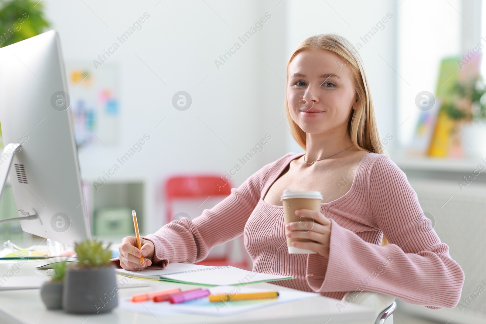 Photo of Designer with paper cup of drink working at table in office