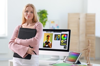 Photo of Beautiful young designer with tablet in office