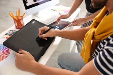 Designers working together with tablets at table in office, closeup