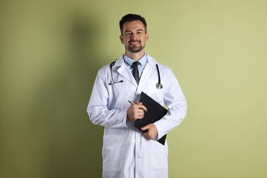 Photo of Smiling doctor with stethoscope and clipboard on olive background