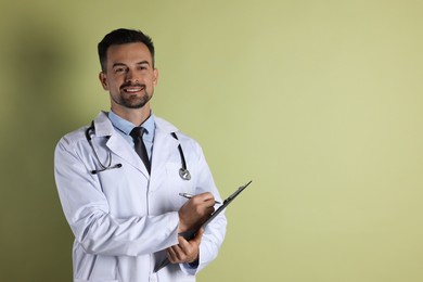 Photo of Smiling doctor with stethoscope and clipboard on olive background, space for text