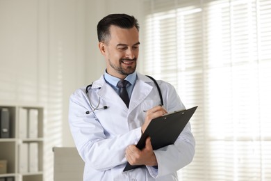 Photo of Smiling doctor with stethoscope and clipboard in clinic