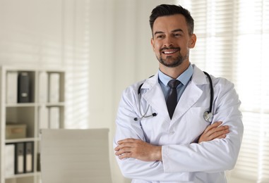 Photo of Smiling doctor with stethoscope in clinic, space for text