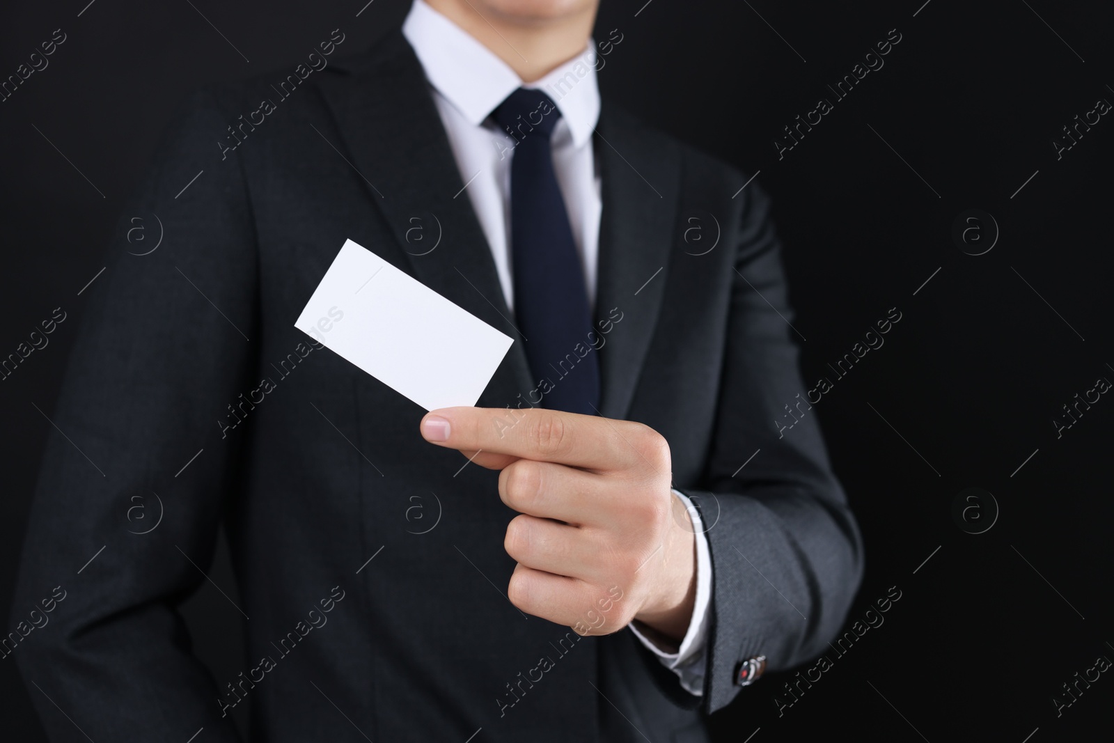 Photo of Man holding blank business card on black background, closeup. Mockup for design