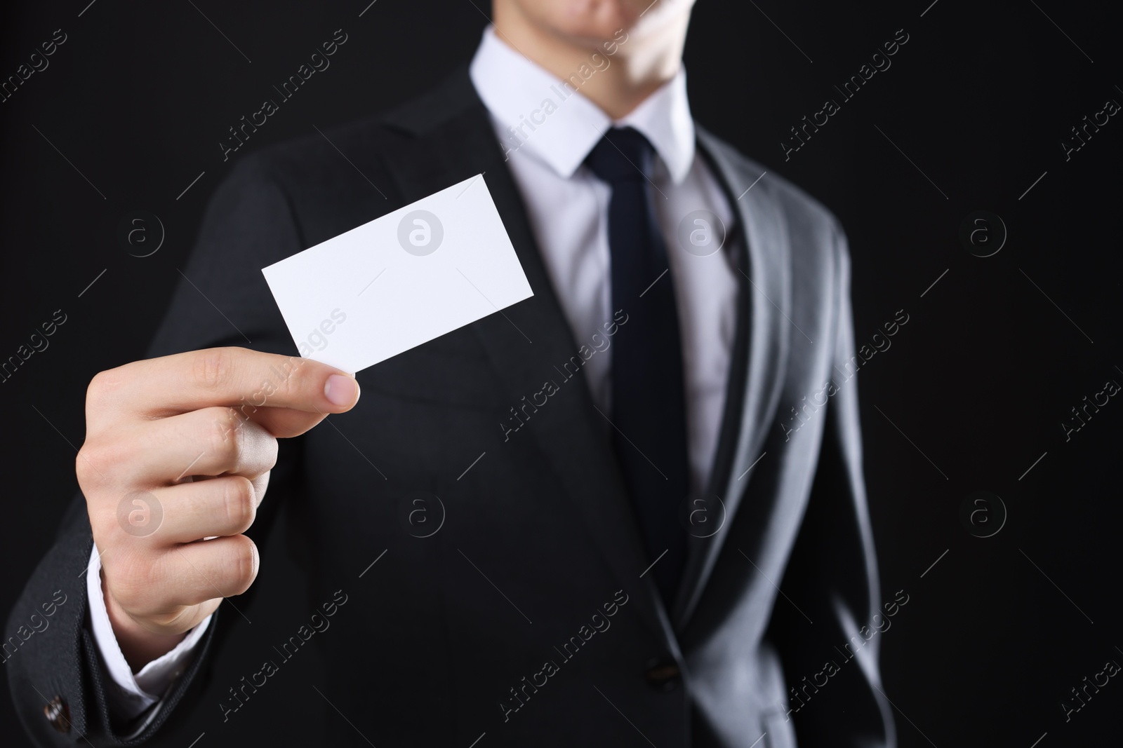 Photo of Man holding blank business card on black background, closeup. Mockup for design