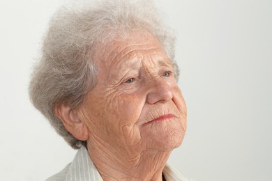 Portrait of senior woman on light grey background, closeup