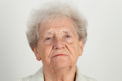 Portrait of senior woman on light grey background, closeup