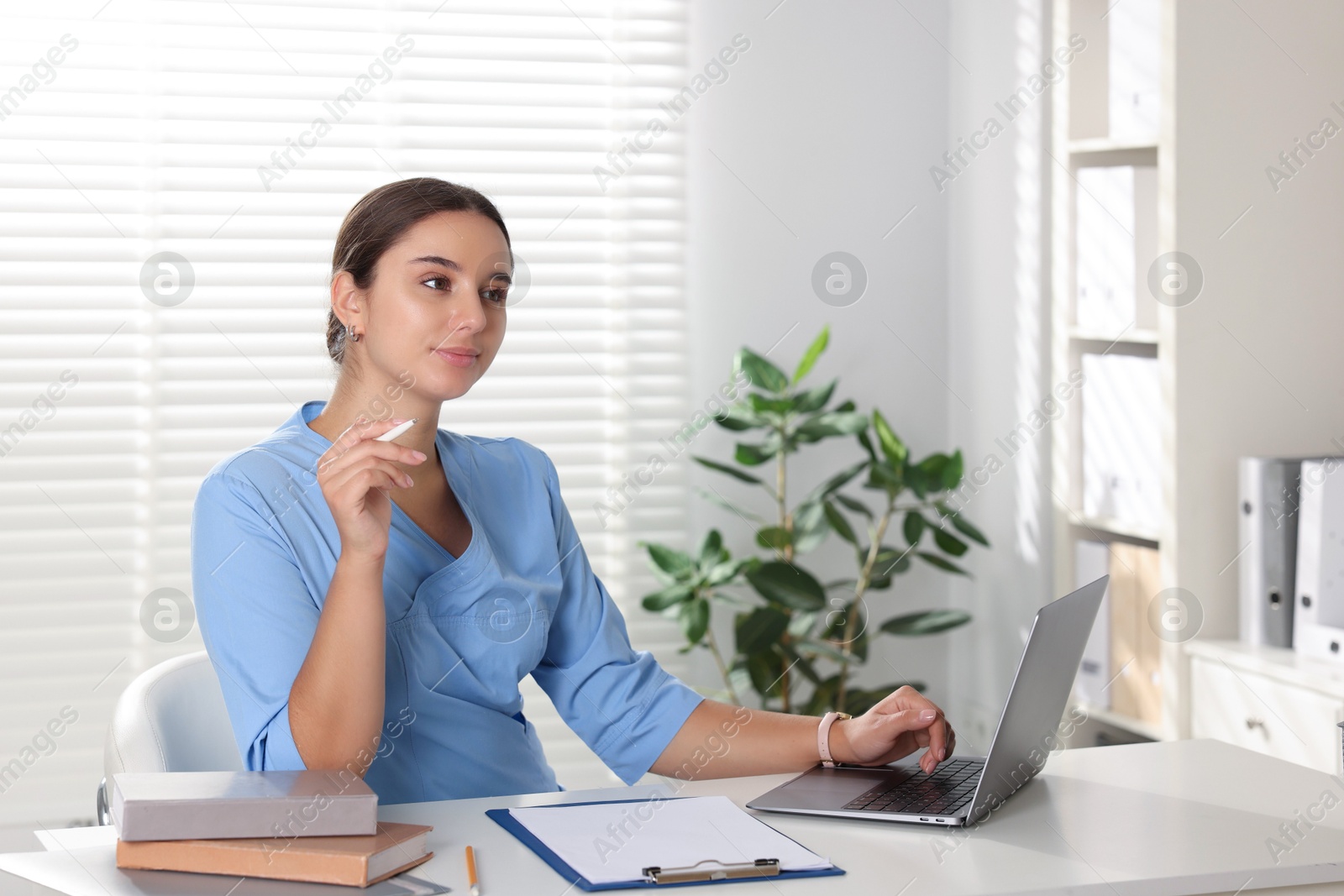 Photo of Medical student studying with laptop at table indoors