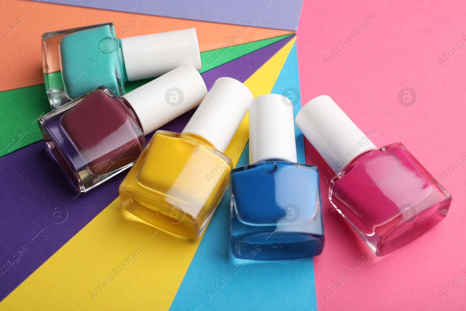 Photo of Set of different nail polishes in bottles on color background, closeup