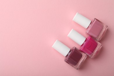 Photo of Set of different nail polishes in bottles on pink background, flat lay. Space for text