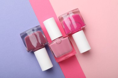 Photo of Nail polishes in bottles on color background, flat lay