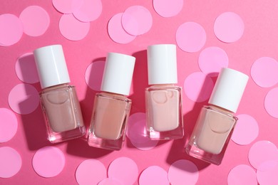 Photo of Set of nude nail polishes in bottles on pink background, flat lay