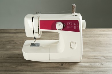 Sewing machine on wooden table against gray background