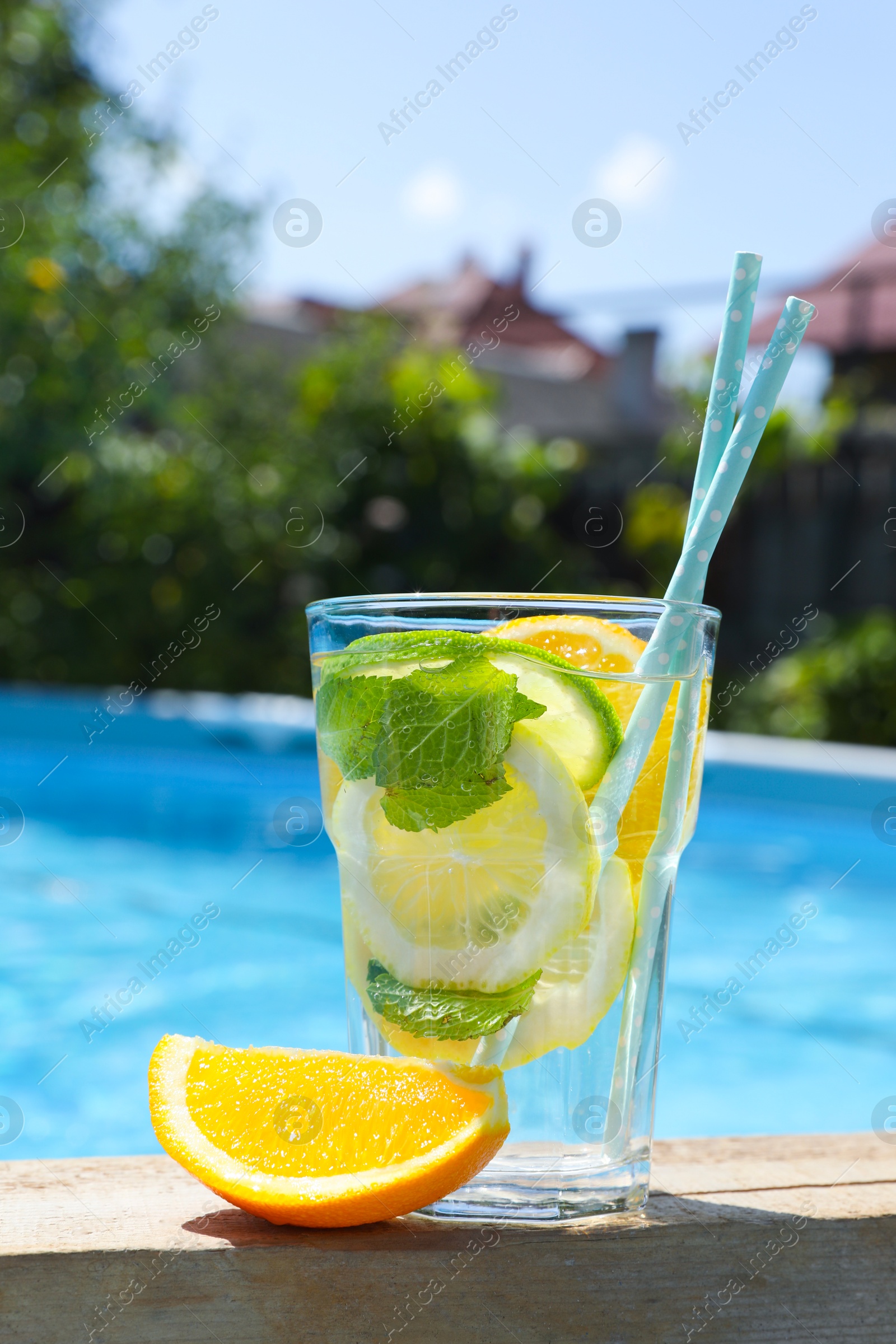 Photo of Tasty cocktail in glass near swimming pool outdoors