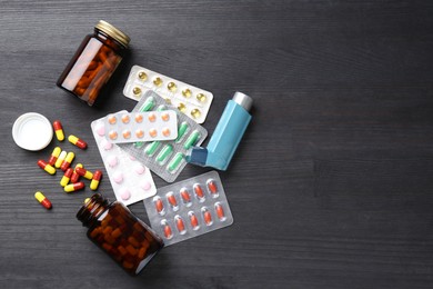 Photo of Pharmacist. Different pills and inhaler on grey wooden table, flat lay. Space for text