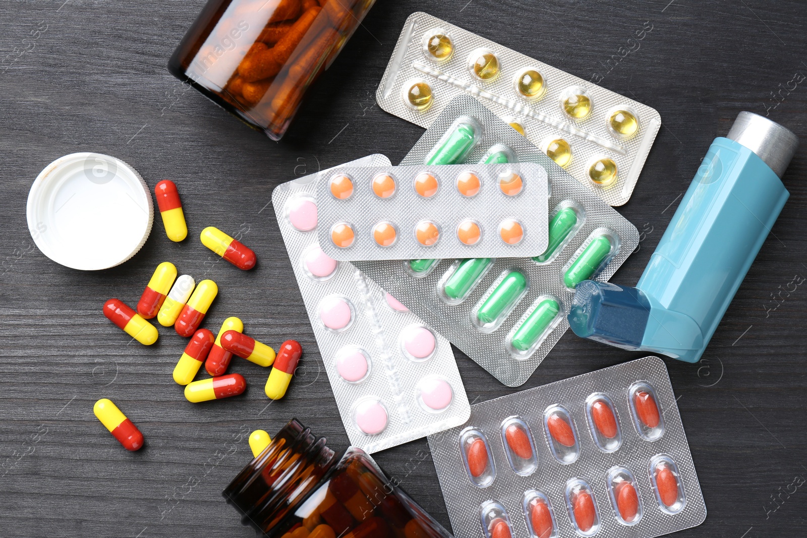 Photo of Pharmacist. Different pills and inhaler on grey wooden table, flat lay