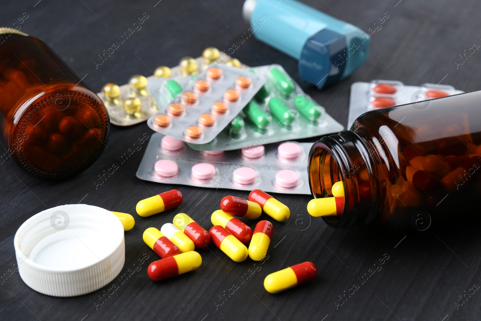 Photo of Pharmacist. Different pills, overturned bottle and inhaler on grey wooden table, closeup