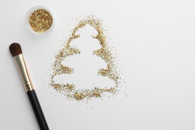 Photo of Christmas tree made of glitter and makeup brush on white background, flat lay. Space for text