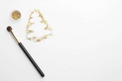 Photo of Christmas tree made of glitter and makeup brush on white background, flat lay. Space for text