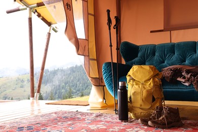 Photo of Comfortable sofa and tourist stuff in glamping site