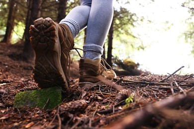 Photo of Hiker in trekking shoes walking in forest, closeup