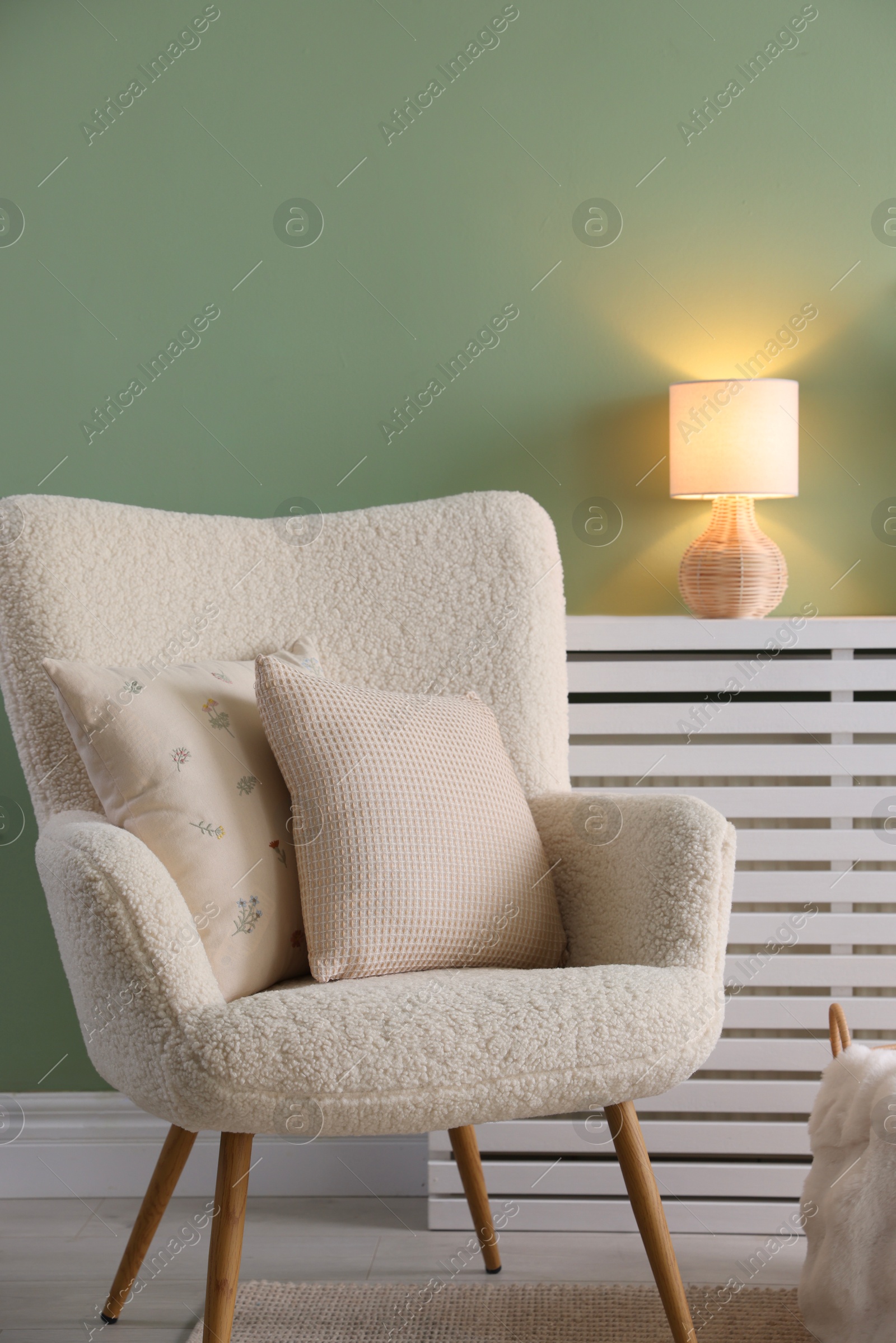 Photo of Two soft pillows on light armchair in living room